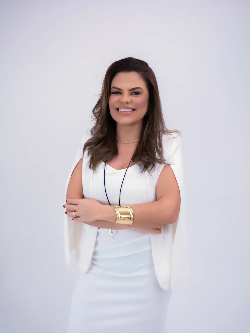 Dra. Charlene Sousa de branco, de braços cruzados, sorrindo
